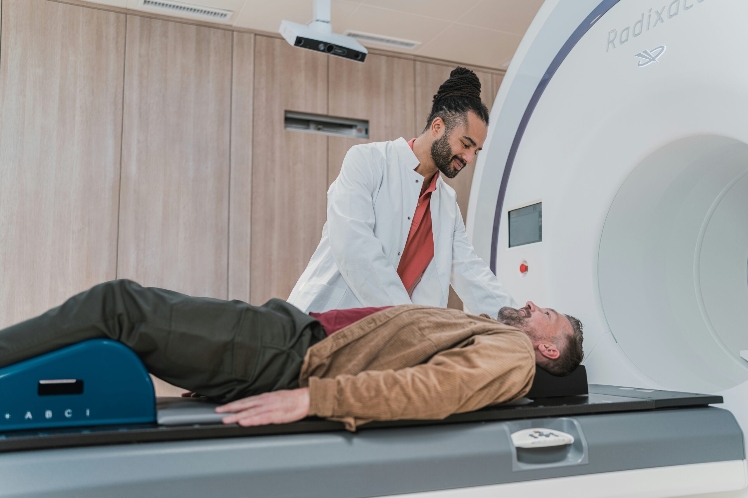 Doctor in a white coat attending to a patient lying on a medical scanning machine, conveying a professional healthcare setting focused on patient care and advanced diagnostics.